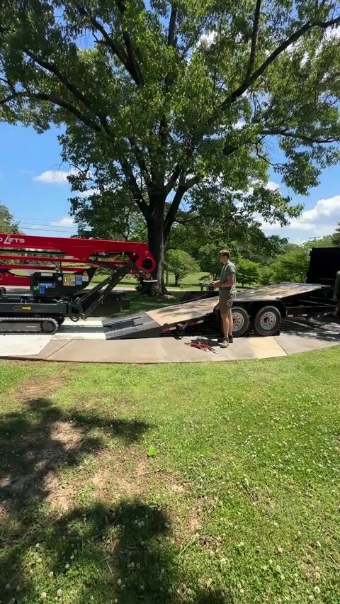 The tracked lift staged on ground protection mats laid across the lawn