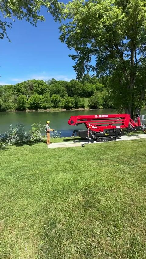 The tracked lift set up on the lawn beside the water, boom folded