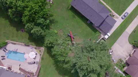 Drone footage looking straight down on the lift set up on the lawn, fully extended into the tree
