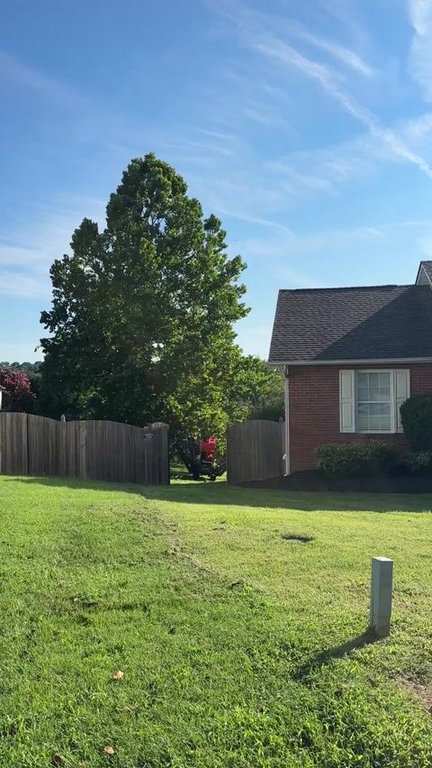 Arborist tracked lift fitting through residential fence gate so that worker can begin removing tree.
